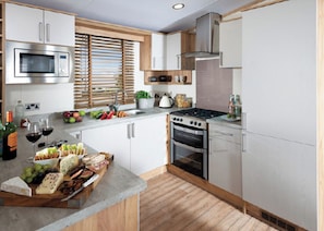 A modern kitchen with stainless steel appliances, wooden cabinets, and a central island with food items.