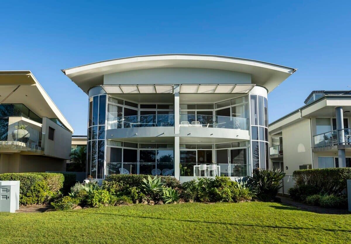 A modern multi-story building with a curved roof and large glass windows.