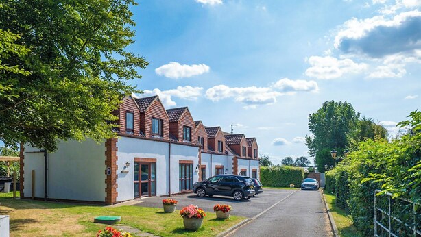 A residential street with houses, parked cars, and flower pots. - 2 Bedroom Apartment with Hot Tub (Thirsk)