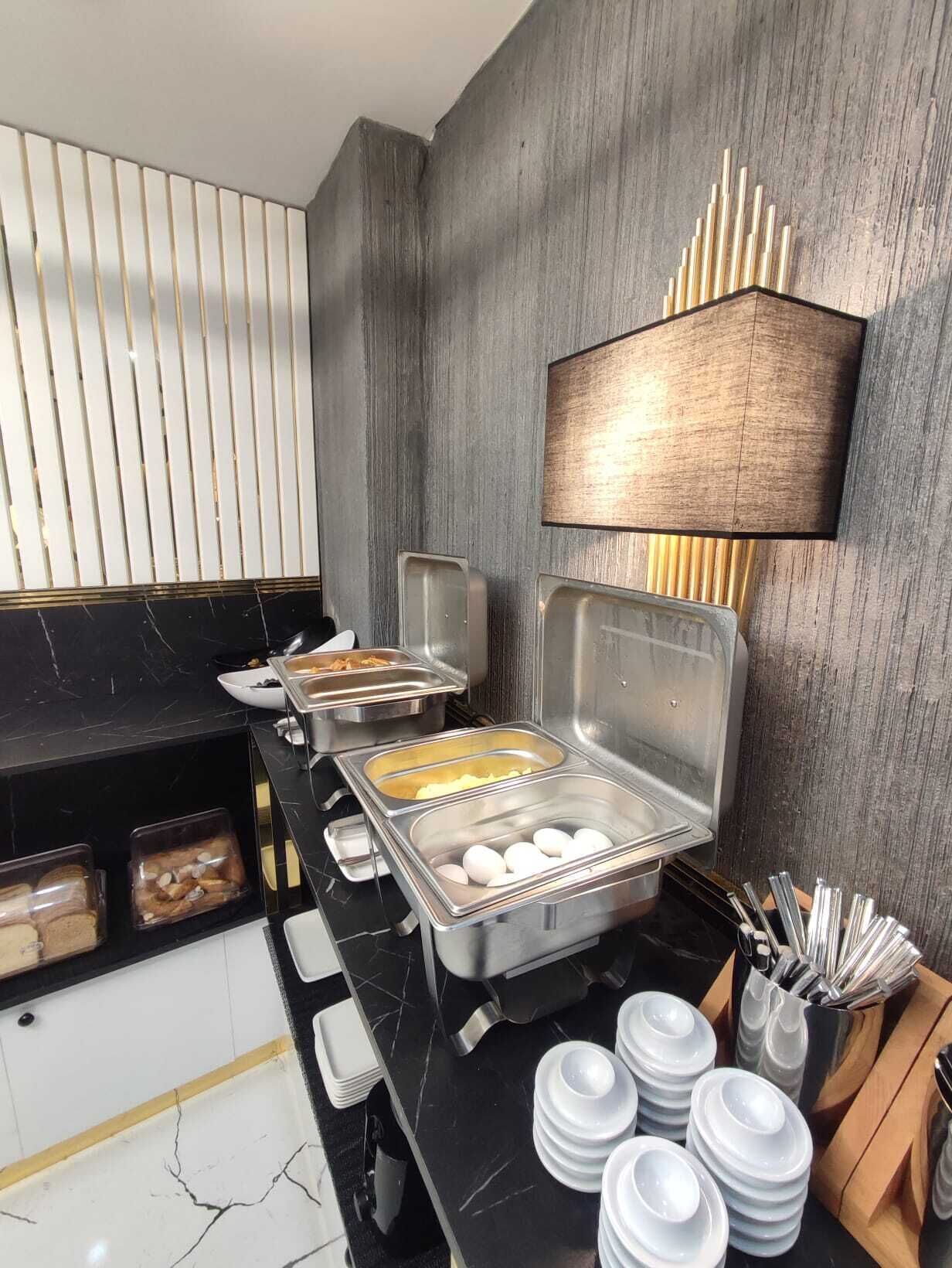 Un buffet proposant une variété de plats, notamment des œufs et du pain, ainsi qu’une lampe fixée au mur.