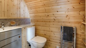 Een badkamer met houten lambrisering, voorzien van toilet, wastafel en handdoekhouder.