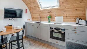 Een moderne keuken met een houten plafond, een inbouwoven, een spoelbak en een eethoek met een tafel en stoelen.
