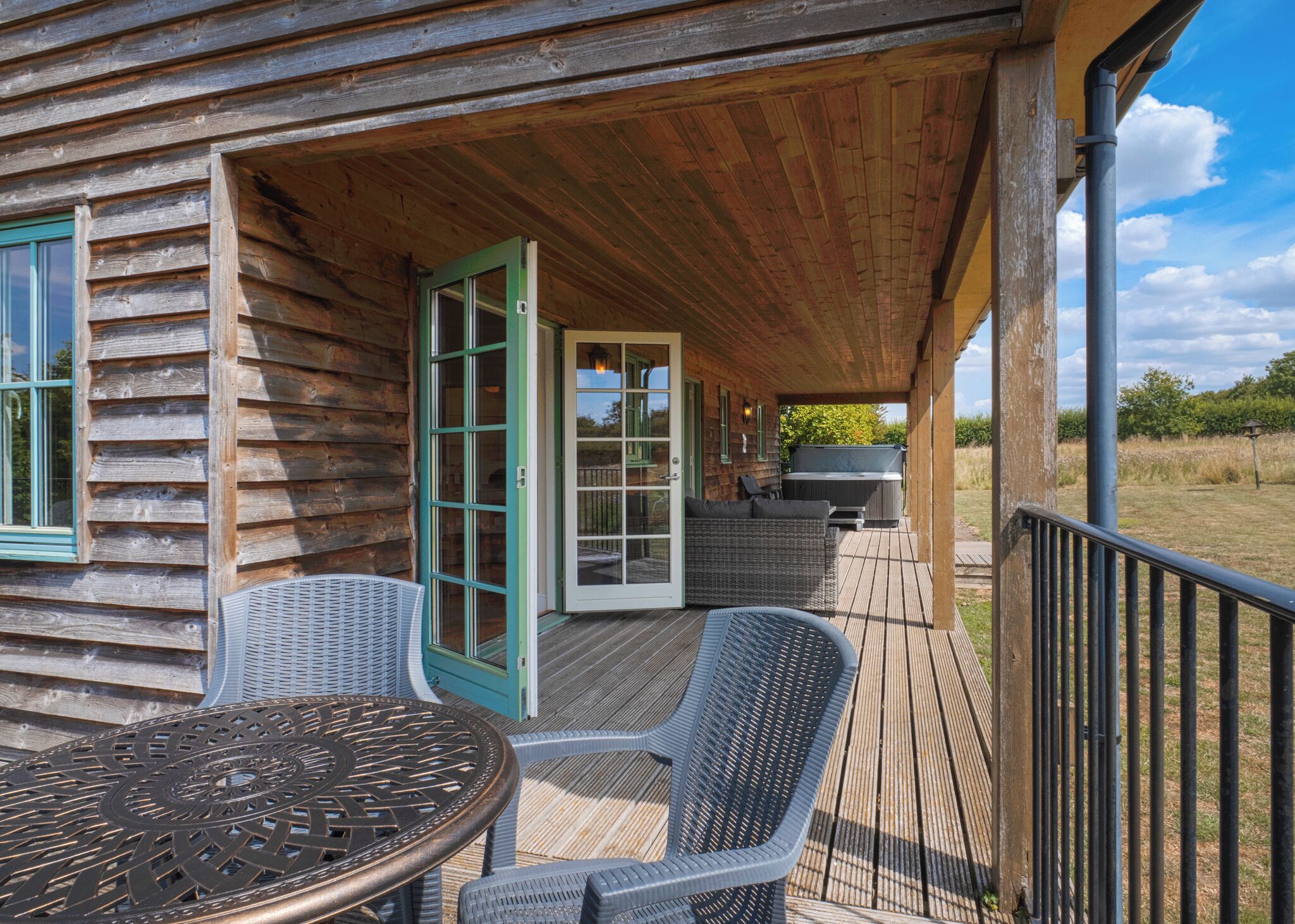 Eine Holzhütte mit überdachter Veranda, Sitzgelegenheiten im Freien und Grillplatz.