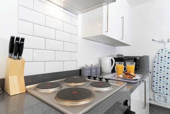 Una cocina moderna con estufa a gas, cafetera y hervidor.