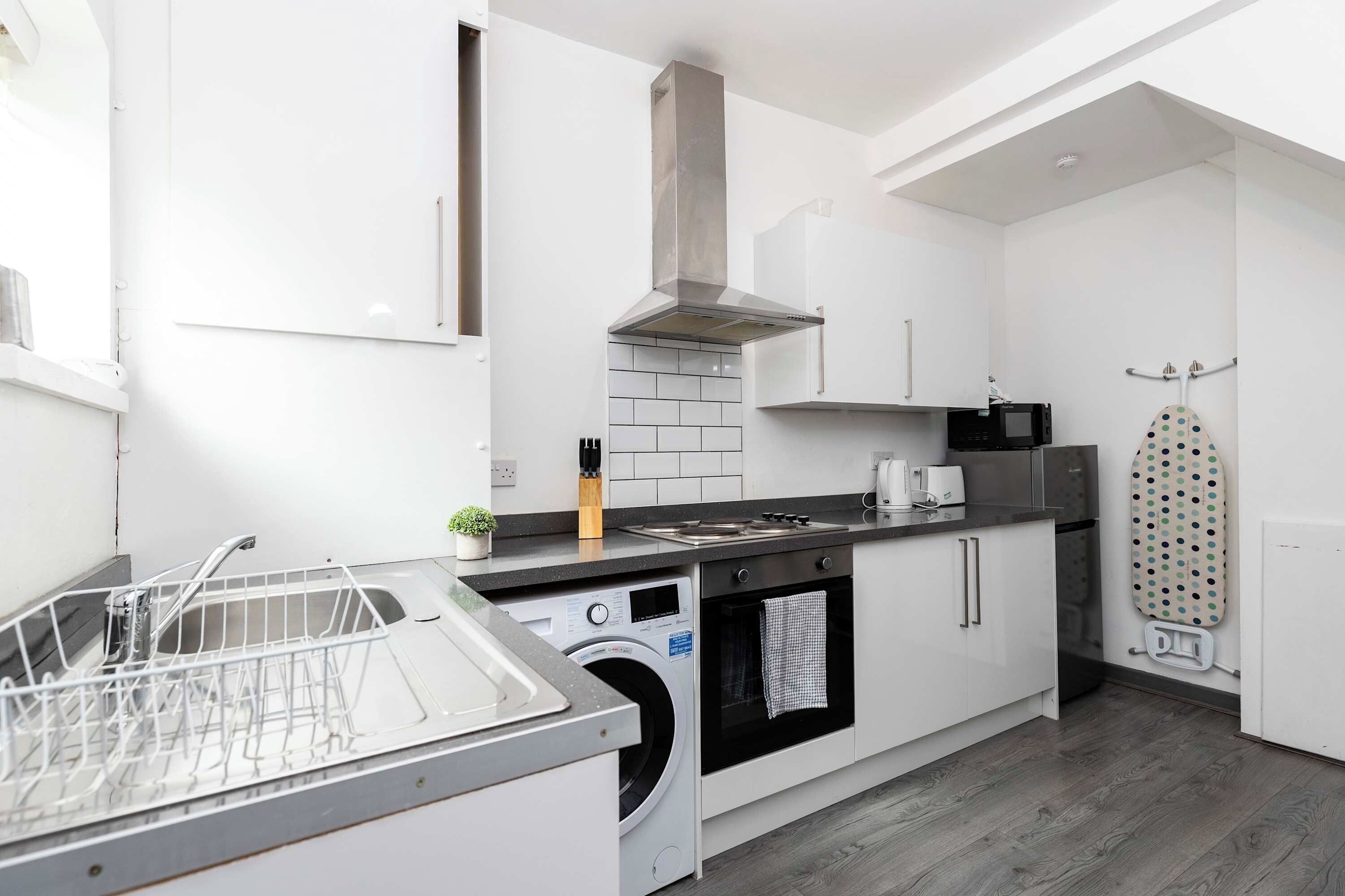 A modern kitchen with a dishwasher, oven, microwave, and a drying rack.