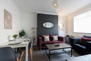 Ein modernes Wohnzimmer mit Essbereich, einer Couch, einem Couchtisch und einem Bücherregal.