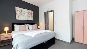 A modern bedroom with a bed, bedside tables, a wardrobe, and a painting on the wall.