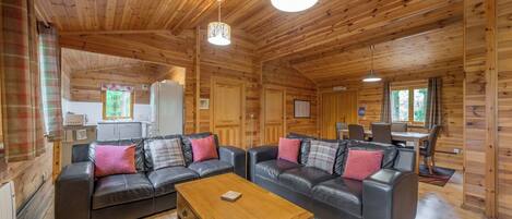 L’intérieur d’un chalet en bois comprend un espace de vie avec deux canapés, une table basse et une table à manger avec des chaises.