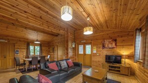 L’intérieur d’un chalet en bois comprend un canapé d’angle, un téléviseur et un coin repas.
