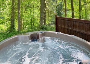 Un bain à remous situé dans une zone boisée, avec une terrasse en bois.