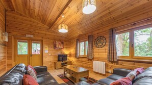 A wooden cabin interior with a sofa, television, and a clock on the wall. - 3 bedroom accommodation in Ellesmere (Ellesmere)