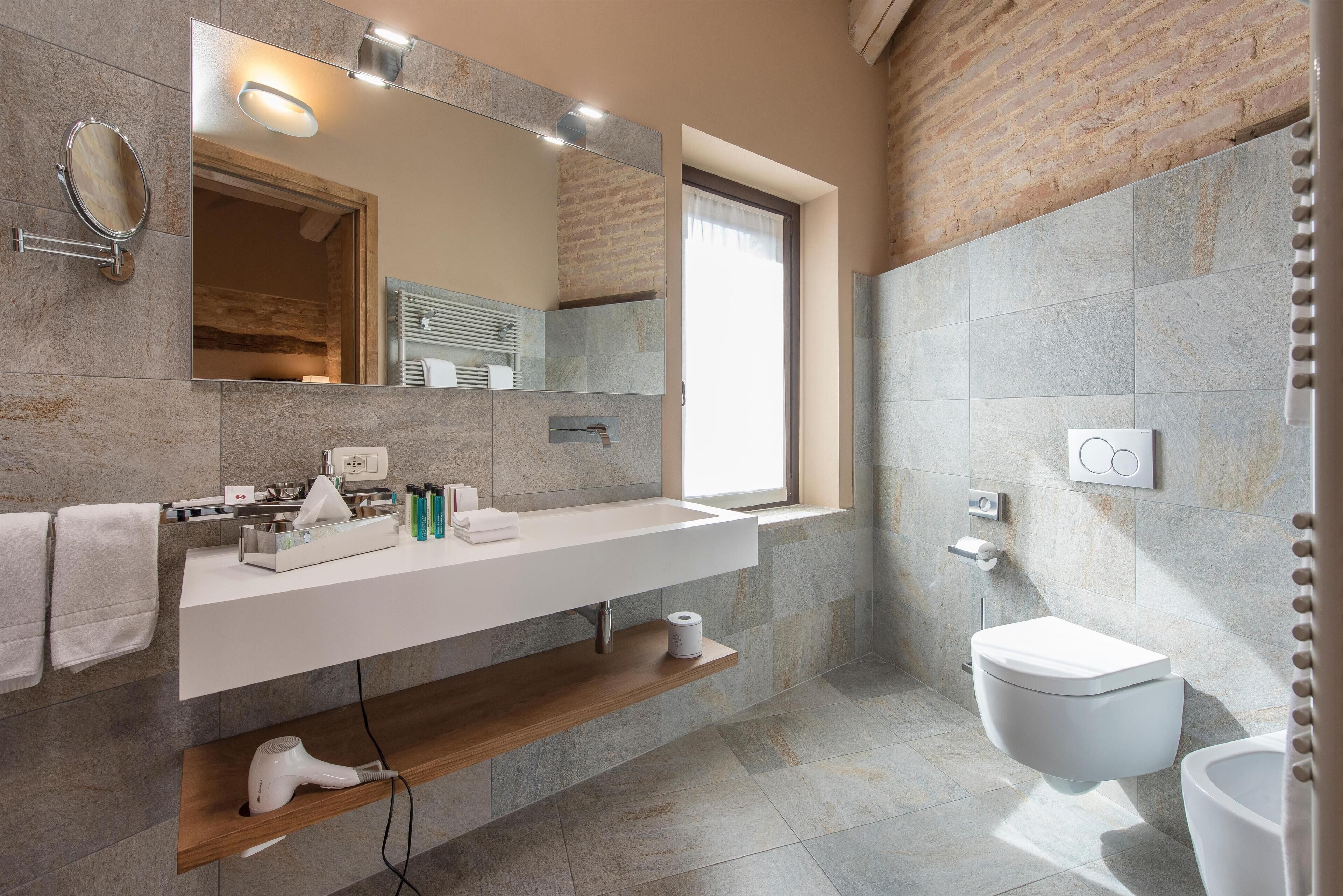 Une salle de bain moderne avec un grand miroir, un lavabo blanc et des toilettes intégrées.