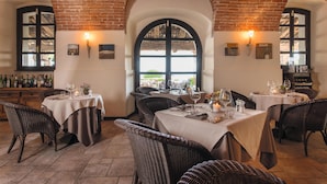 Un restaurant aux murs de briques, aux fenêtres en arc de cercle et aux meubles en osier. Les tables sont décorées de bougies et de verres à vin.