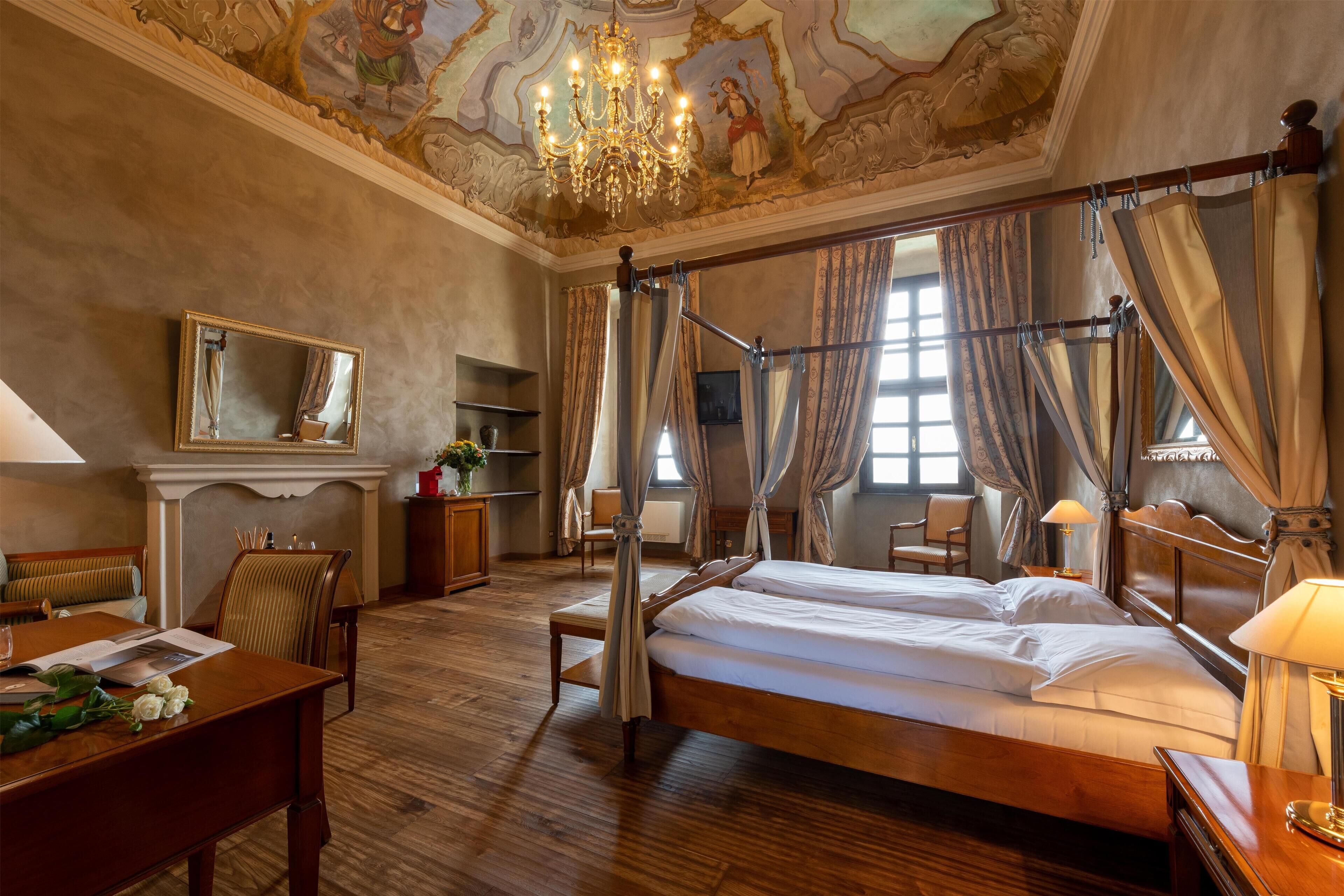 A four-poster bed with a canopy, a chandelier, and a fireplace.