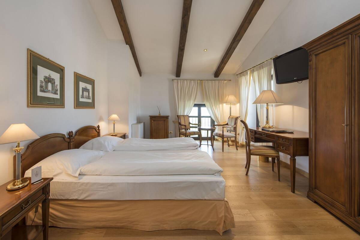 Une chambre d’hôtel avec deux lits, un bureau, une télévision et des tableaux encadrés au mur.
