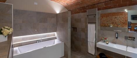 A modern bathroom with a large bathtub, a vanity with a mirror, and a brick ceiling.
