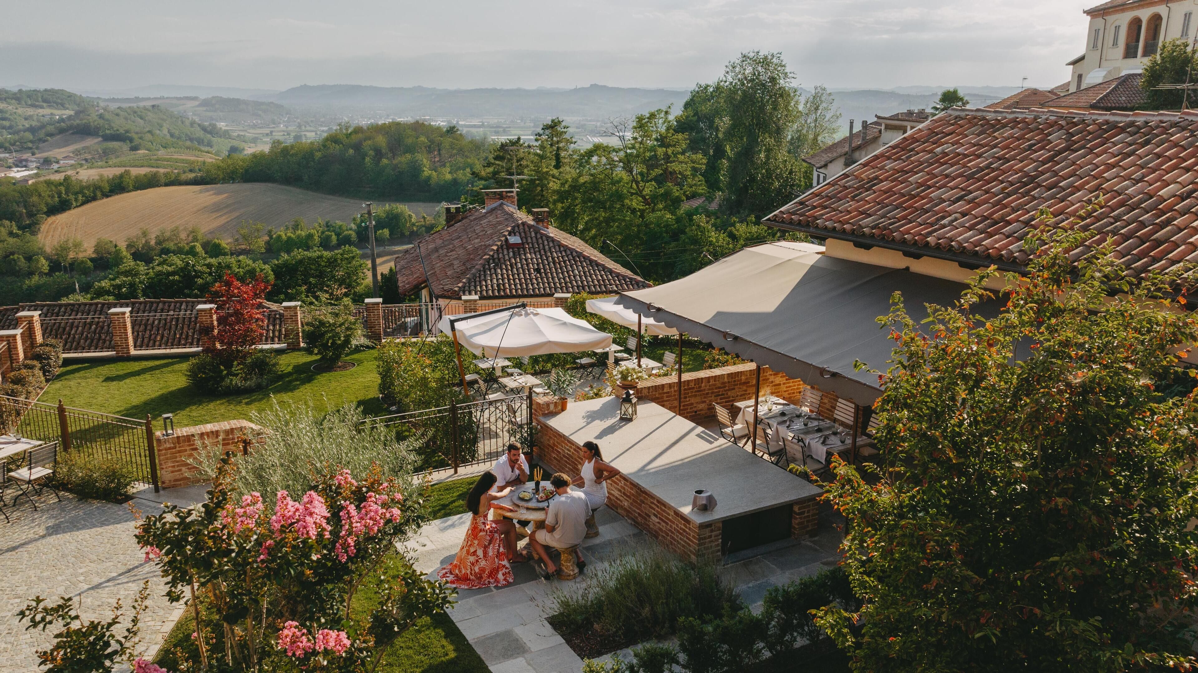 A courtyard with outdoor seating, a brick building, and a view of the countryside.