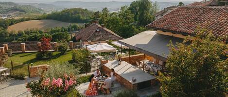 A courtyard with outdoor seating, a brick building, and a view of the countryside.