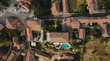 An aerial view of a residential area with terracotta-roofed houses, a central swimming pool, and a stop sign.