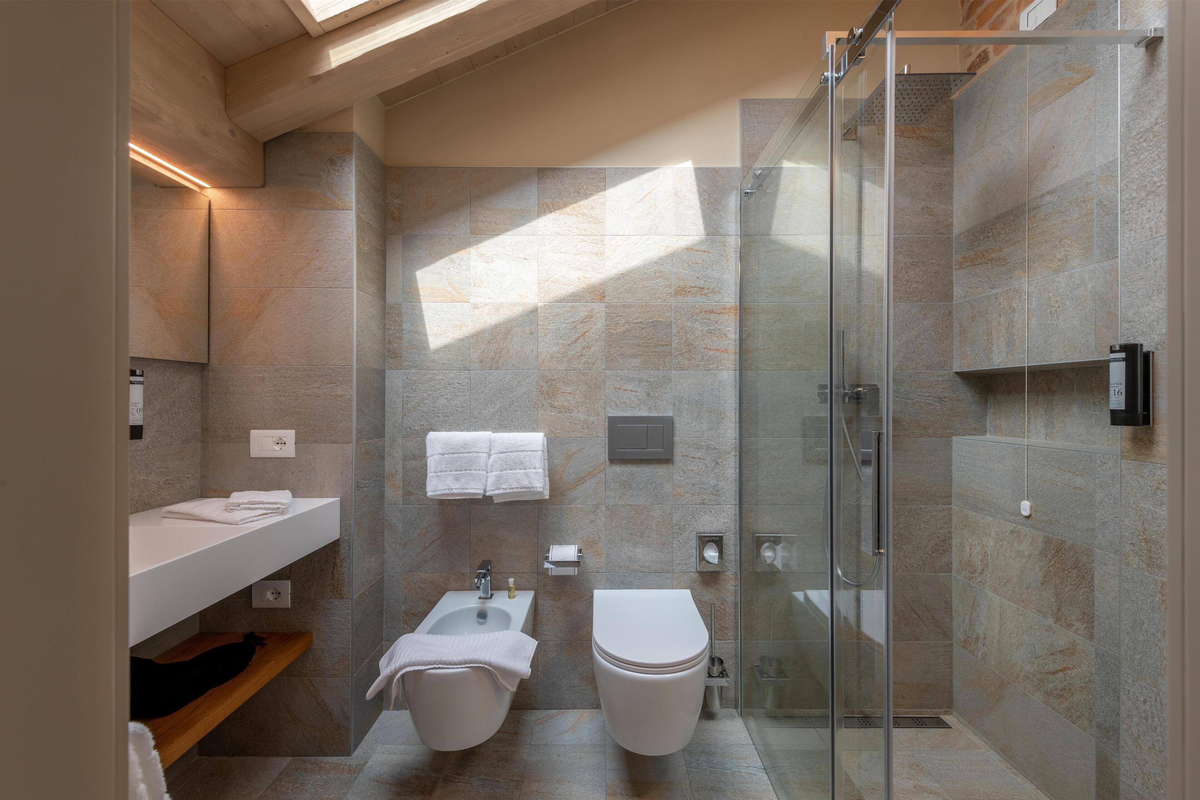 Un baño moderno con cabina de ducha de vidrio, un lavabo blanco y un inodoro.