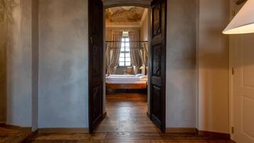 Un pasillo que conduce a un dormitorio con una cama, suelo de madera y un techo con diseño decorativo.