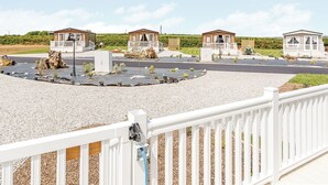Un lotissement résidentiel fermé, composé de plusieurs petites maisons, une allée pavée et un espace recouvert de gravier agrémenté de plantes.