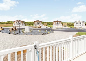 Un área residencial cerrada con varias casas pequeñas, un camino pavimentado y una zona con grava y plantas.