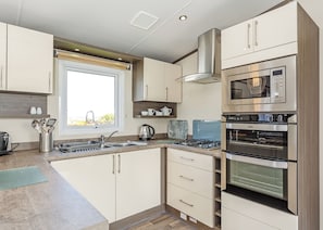 Una cocina moderna con ventana, electrodomésticos de acero inoxidable y armarios de madera.