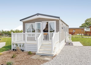 A small, single-story mobile home with a white porch and a staircase leading to the entrance.