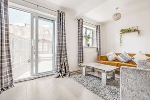 Een moderne woonkamer met een bank, een salontafel en een groot raam met gordijnen.