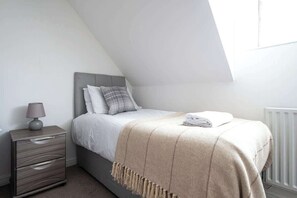 Ein Schlafzimmer mit einem Bett, einem Nachttisch, einer Lampe und einer Heizung.
