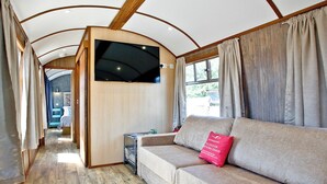 Un interior de caravana acogedor con sofá, televisor y suelo de madera.