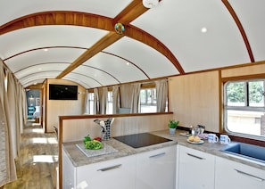 A kitchen with a wooden ceiling, a sink, and a window.