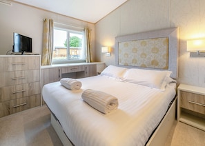 A hotel room with a bed, a desk, a television, and a window with curtains.