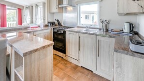 A modern kitchen with a central island, stainless steel appliances, and light wood cabinetry.