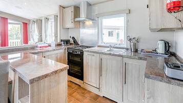 A modern kitchen with a central island, stainless steel appliances, and light wood cabinetry.