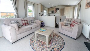 A living room with two sofas, a coffee table, and a kitchen area in the background.