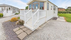 A mobile home with a porch, steps, and a gravel driveway.
