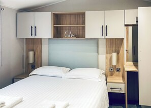 Una habitación de hotel con cama, mesita de noche, armario y espejo.