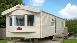 A caravan with a 'Carnaby Ashdale' sign, a covered porch, and a picnic table.