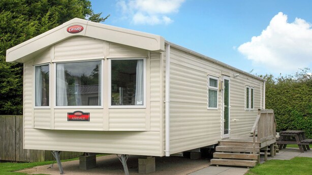 A caravan with a 'Carnaby Ashdale' sign, a covered porch, and a picnic table. - 2 bedroom accommodation in Cowden, Nr Hornsea (Cowden, Nr Hornsea)