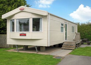 A caravan with a 'Carnaby Ashdale' sign, a covered porch, and a picnic table.