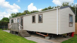 A mobile home with a front porch, a set of stairs, and a small deck. - 2 bedroom accommodation in Cowden, Nr Hornsea (Cowden, Nr Hornsea)