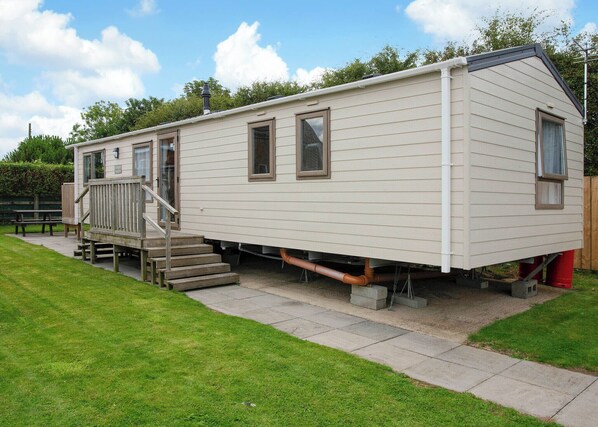 A mobile home with a front porch, a set of stairs, and a small deck.