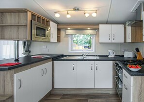 A modern kitchen with white cabinets, a black countertop, a window, and a stove.
