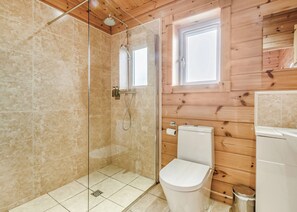 Ein Badezimmer mit Duschkabine, Toilette und Fenster.