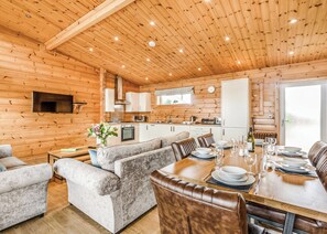 A log cabin interior with a dining area, kitchen, and living room.