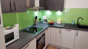 A modern kitchen with a microwave, stove, and sink. - FeWo Wildflecken - Holiday apartment Rhön new building 2021 (Wildflecken)