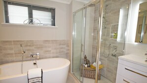 Une salle de bain moderne avec une baignoire sur pieds, une douche à parois de verre et un meuble-lavabo avec des tiroirs.