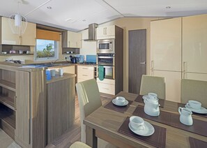 A modern kitchen with a central island, built-in oven, microwave, and a dining area with a table set for four.